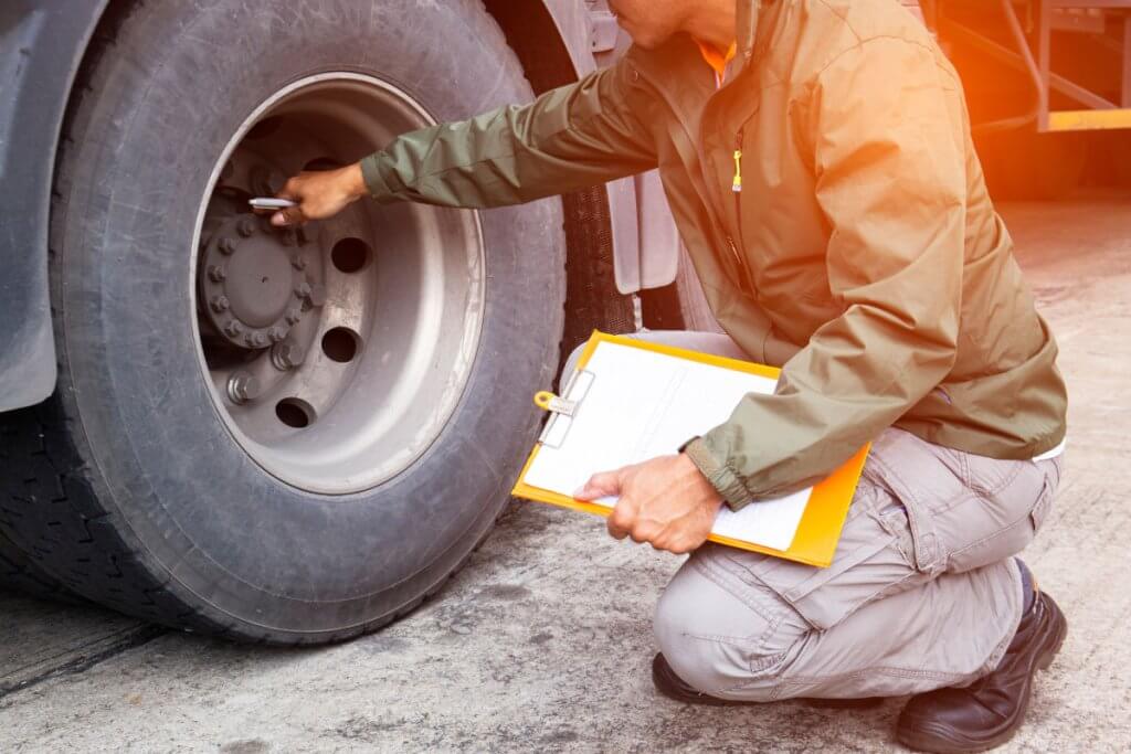 Mechanic adjusting commercial truck brakes to correct top FMCSA vehicle inspection violation