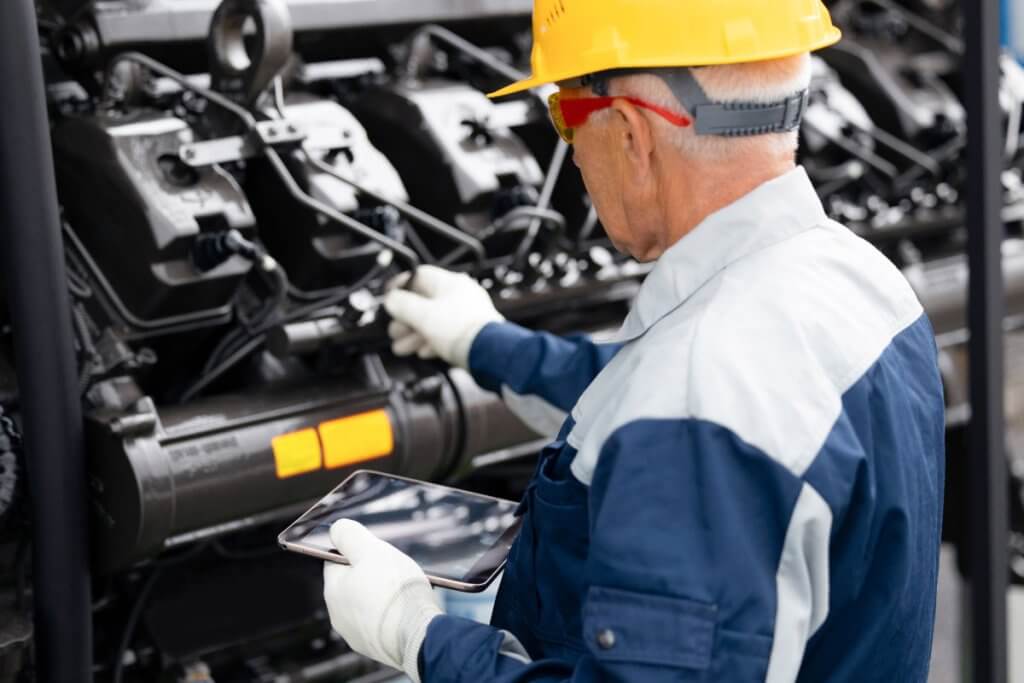 Mechanic inspecting semi truck engine during preventative maintenance to support fleet compliance tracking